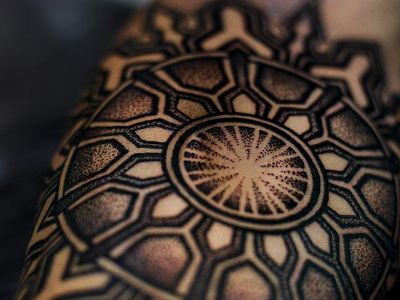 The tattoo is shaped like a sun with a specific pattern designs to it.